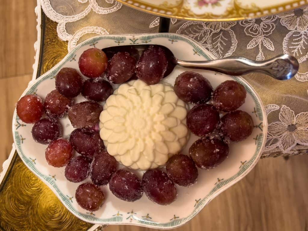 cake with gold frosting, tarts, and French cream complemented with sugared grapes
