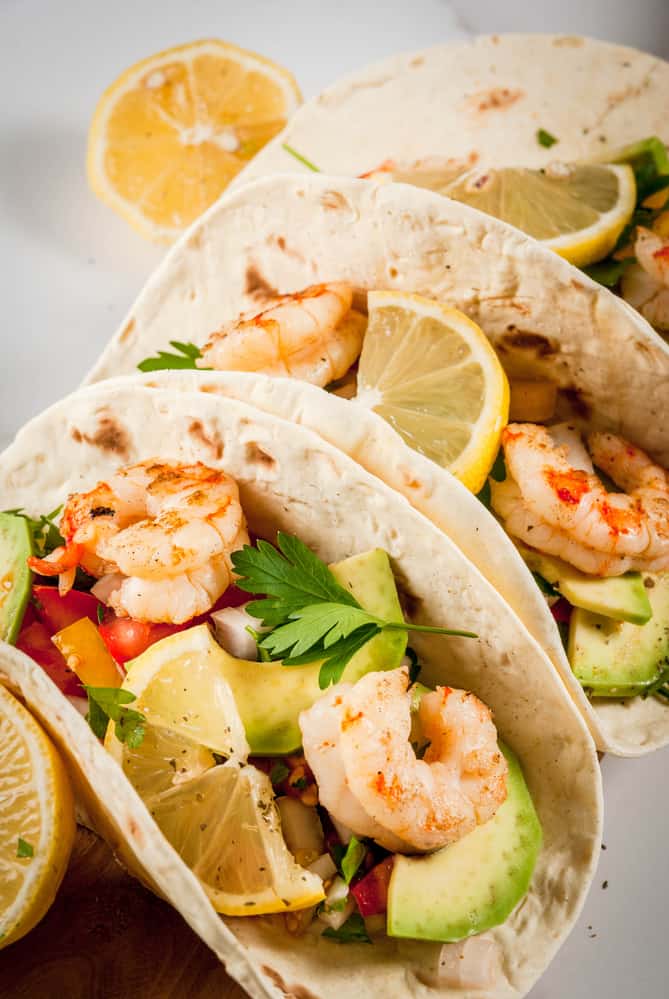 Tortilla tacos with traditional homemade salsa salad, parsley, fresh lemon, avocado and grilled shrimp pawns