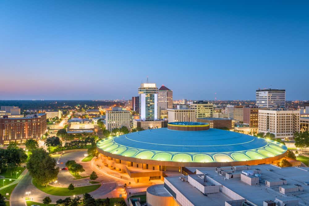 Downtown city skyline at dusk with a prominent circular building in the foreground.