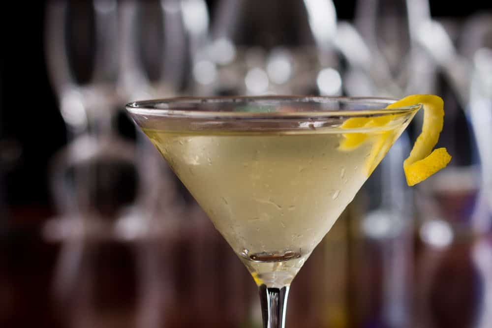 Classic martini cocktail with lemon twist garnish on a bar counter.