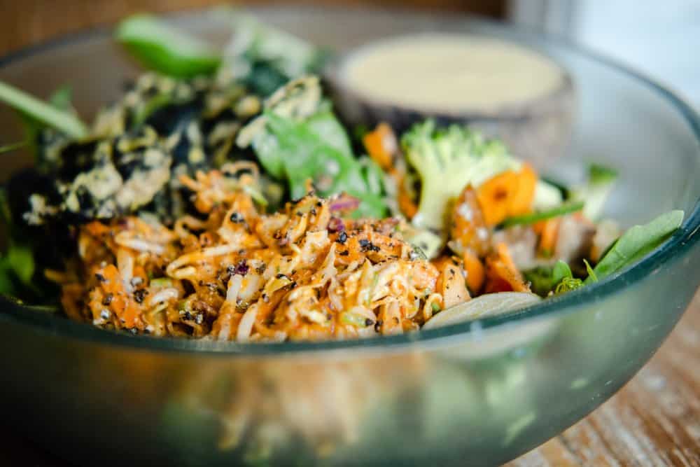 Fresh vegetable salad with shredded chicken and creamy dressing in a glass bowl.