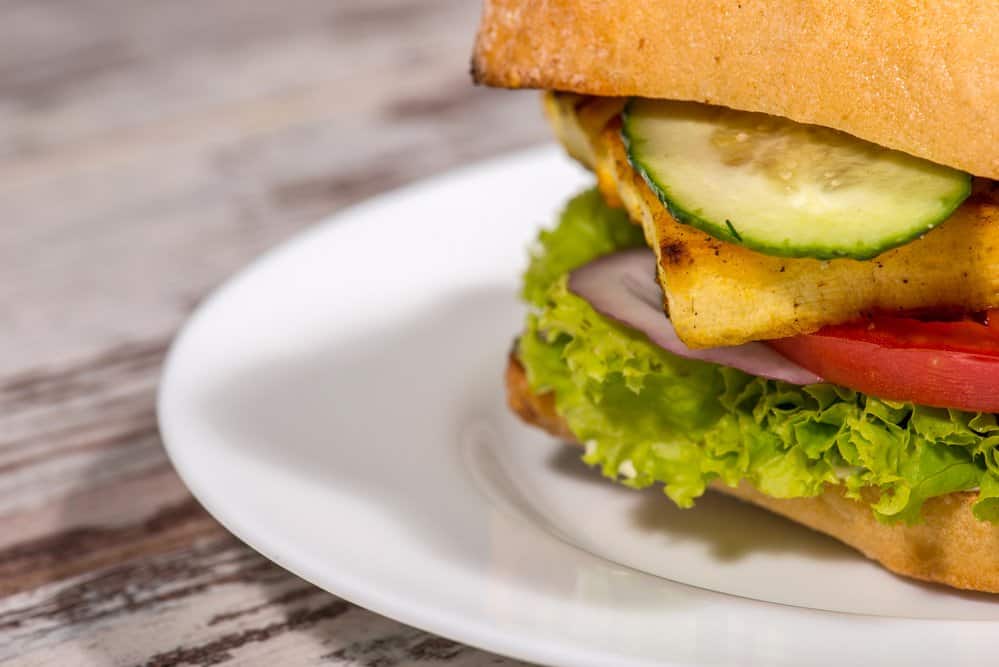 Fresh veggie sandwich with cucumber, tomato, lettuce on whole grain bread.