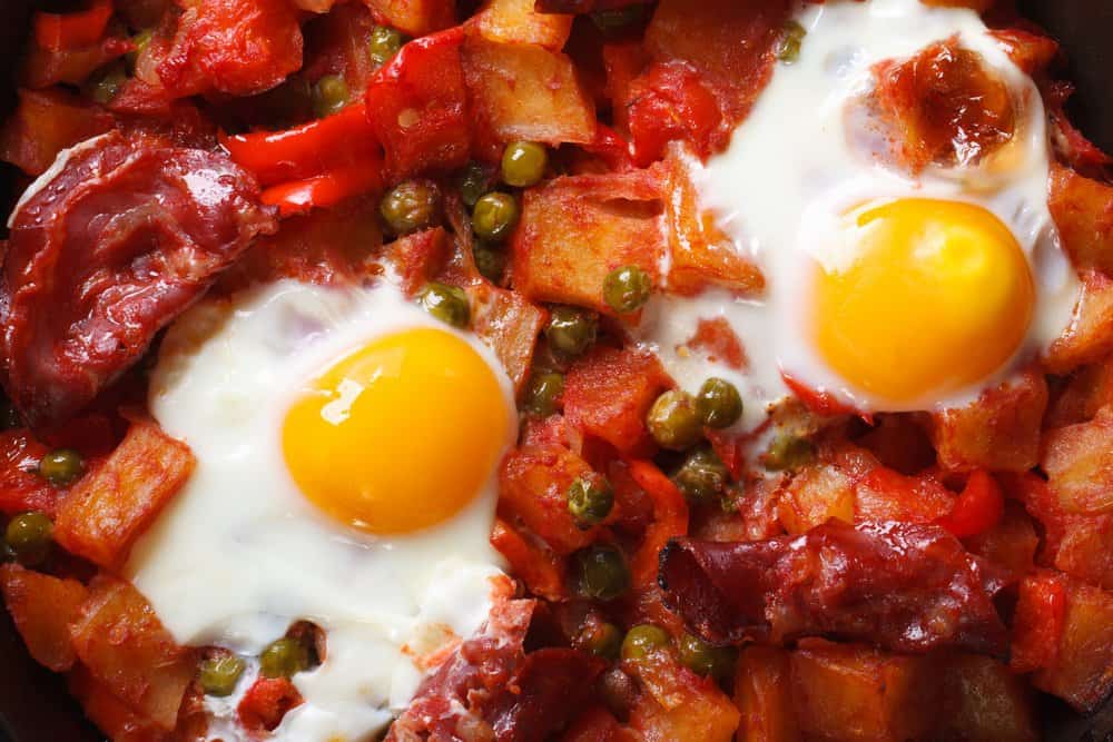 Hearty breakfast hash with eggs, bacon, potatoes, and vegetables.