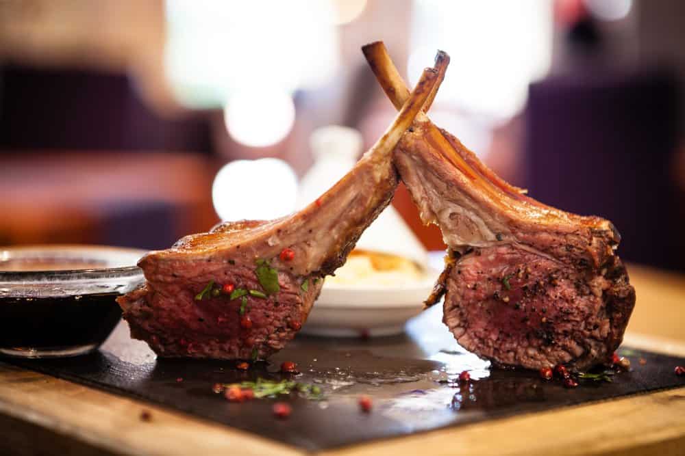 Juicy, perfectly cooked lamb chops on a wooden serving board.