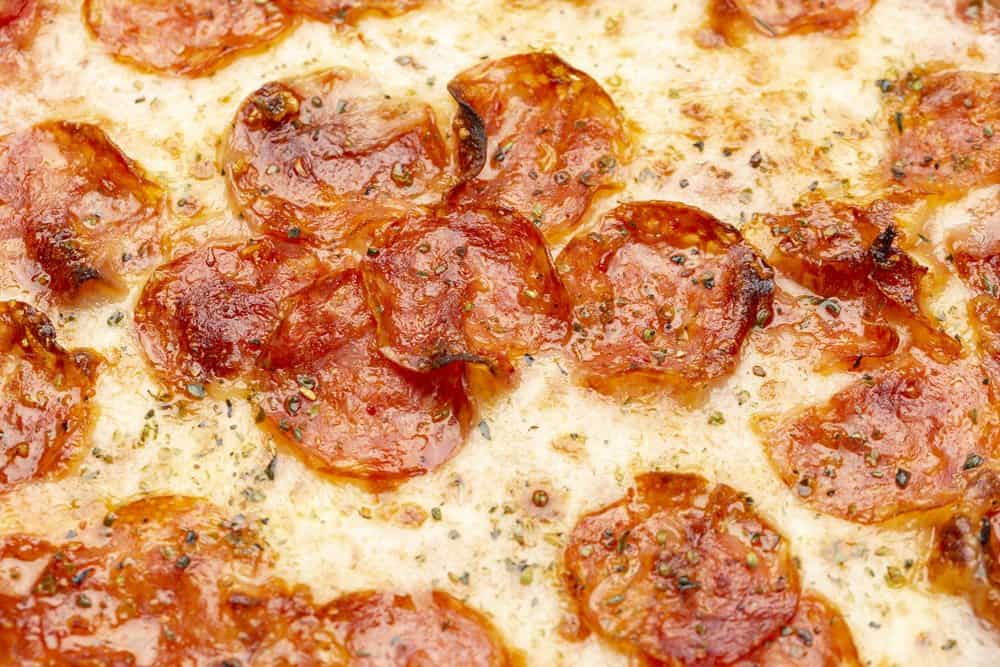 Close-up of pepperoni pizza with melted cheese and herbs.