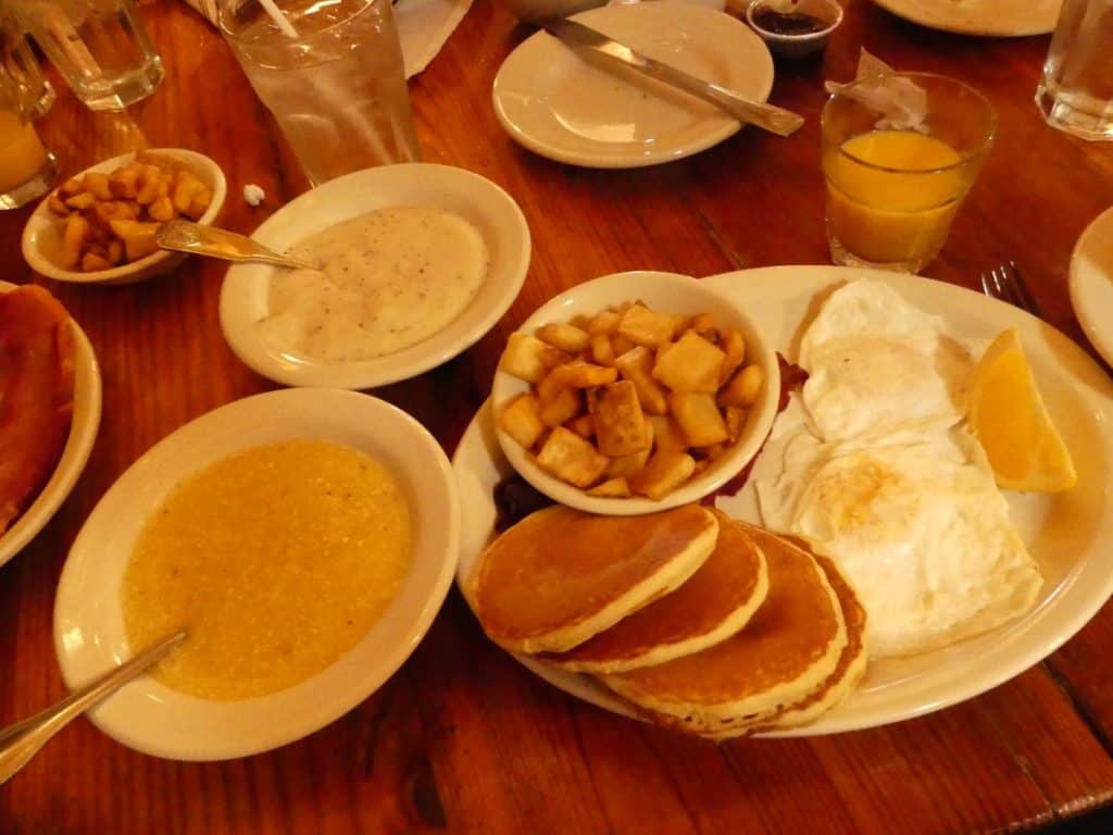 Traditional breakfast with eggs, pancakes, and side dishes on a wooden table.